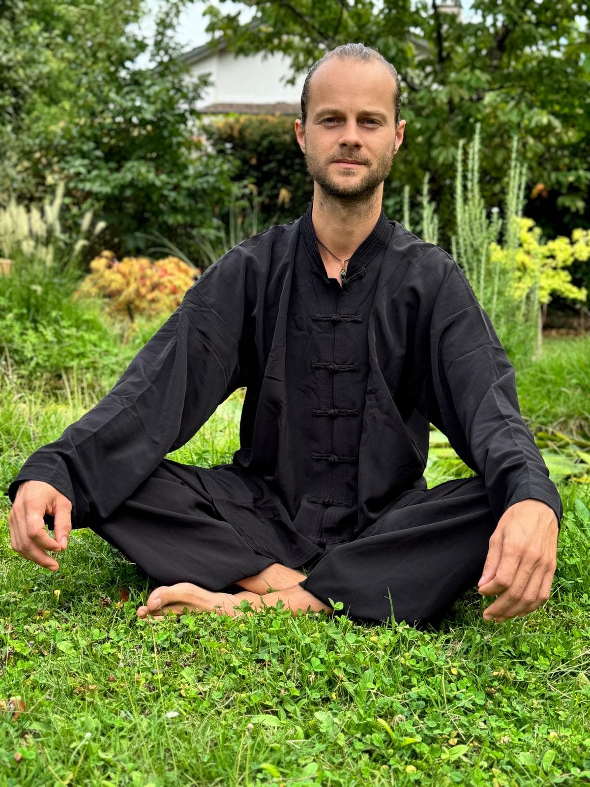 Romain Airault assis en tenue traditionnelle, dans le jardin
